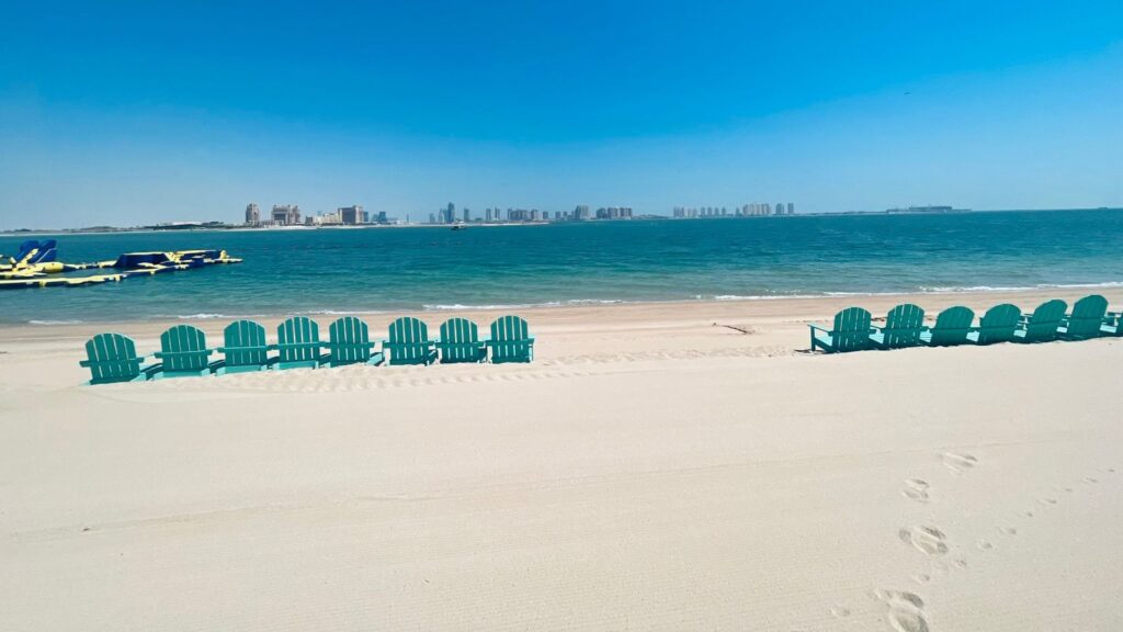 Strand mit türkisen Stühlen eines Beach Clubs in Doha