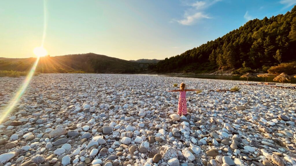 Kind am Fluss bei Sonnenuntergang auf unserem Albanien-Roadtrip