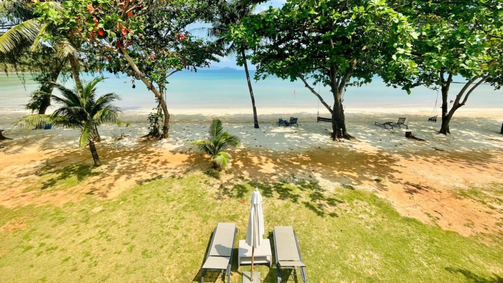 Blick von einer Hotelanlage mit Liegen und Palmen auf das Meer im Koh Chang Archipel