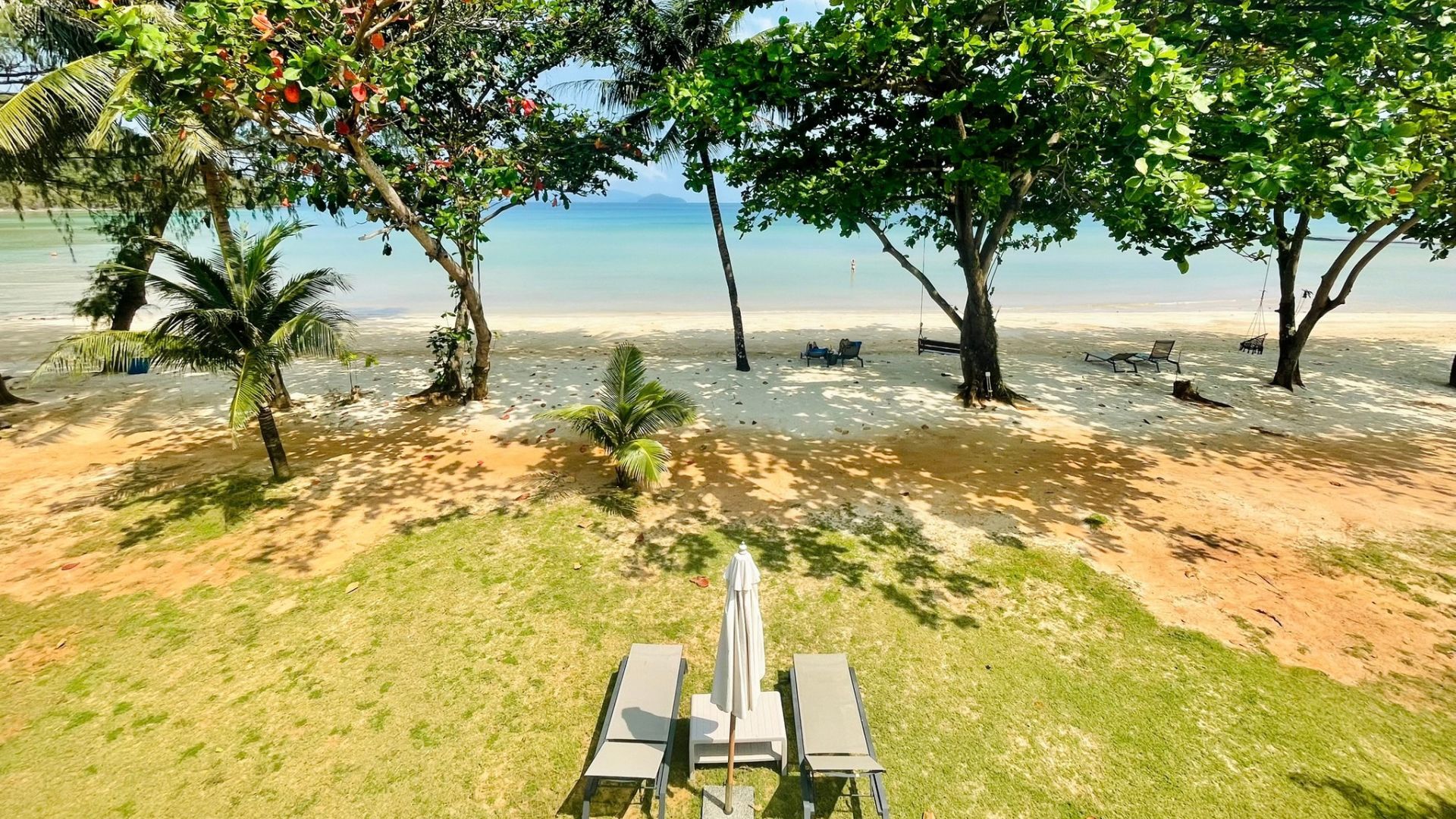 Blick von einer Hotelanlage mit Liegen und Palmen auf das Meer im Koh Chang Archipel